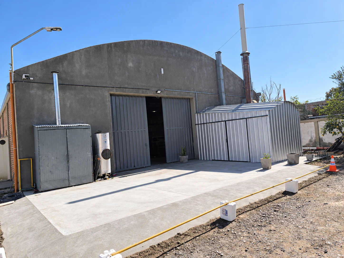 Plataforma de hormigón frente a una nave industrial y cerramiento metálico lateral